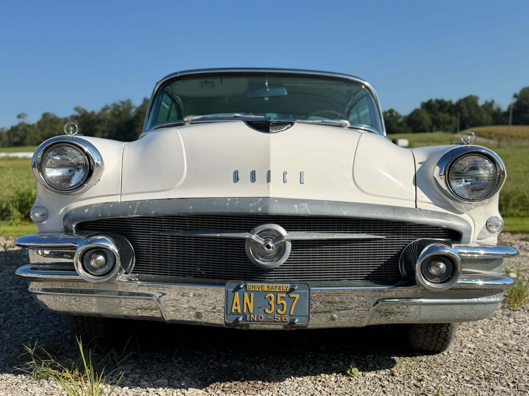 Low front view of a white 1956 Buick with chrome bumper and license plate