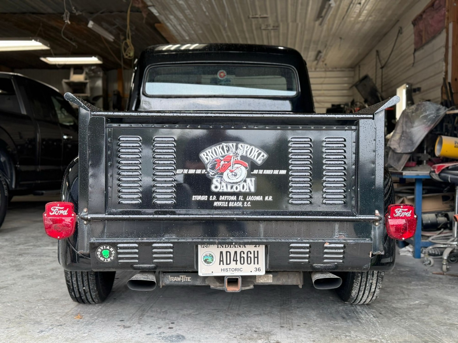 Black Ford pickup from behind with a louvered tailgate and red Ford tail lights