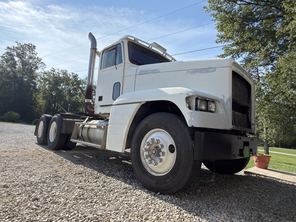 White Freightliner day cab tractor parked on gravel